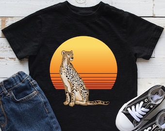 May include: Black t-shirt with a graphic of a cheetah standing in front of a sunset. The sunset is orange and yellow with red stripes.