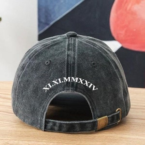 Może przedstawiać: Czarna bejsbolówka z denimu z regulowanym paskiem. Z tyłu czapki znajduje się białe haftowane logo "XI.XI.MMXXIV".