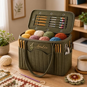 Peut inclure: Un sac de rangement pour fil en tissu vert olive avec un couvercle articulé doté de boucles élastiques internes pour crochets. L'avant est brodé du prénom Amelia et d'un muguet. Il contient plusieurs pelotes de laine et des crochets.