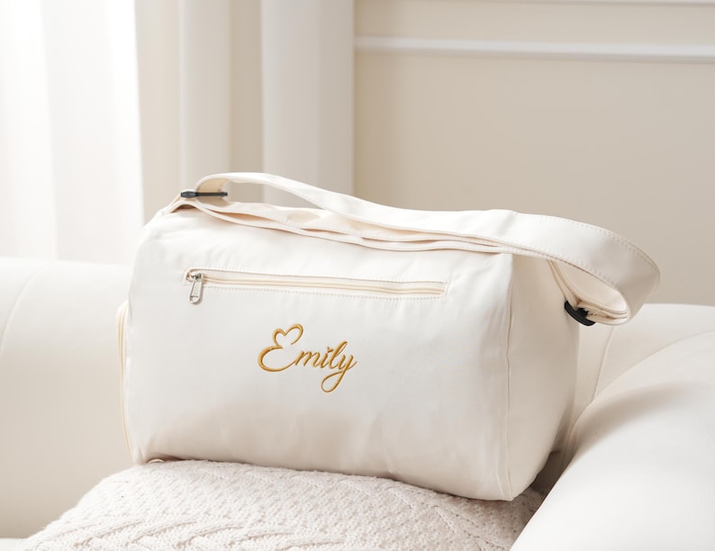 May include: A white canvas duffel bag with a gold embroidered heart and the name "Emily".