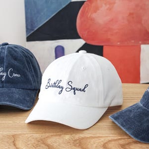 K&ouml;nnte beinhalten: Wei&szlig;e Baseballkappe mit einer dunkelblauen Stickerei mit der Aufschrift "Birthday Squad".