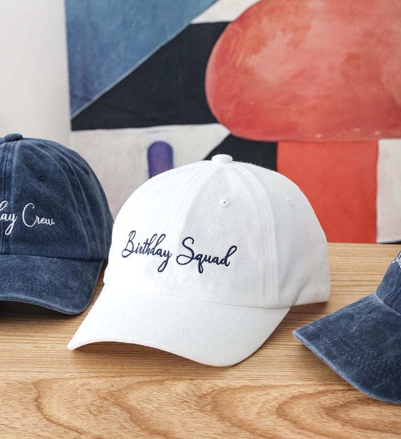 K&ouml;nnte beinhalten: Wei&szlig;e Baseballkappe mit einer dunkelblauen Stickerei mit der Aufschrift "Birthday Squad".