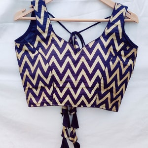 May include: A black and gold sleeveless blouse with a chevron pattern and a tie at the back.