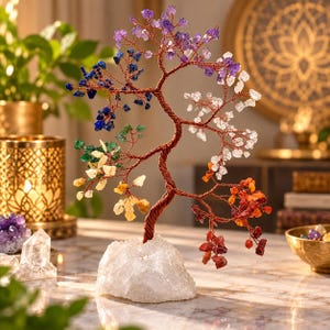 Pode incluir: Uma escultura decorativa de árvore de arame com ramos adornados com fragmentos de pedras preciosas multicoloridas, incluindo pedras roxas, azuis, verdes, amarelas, laranjas, vermelhas e transparentes, fixada numa base de cristal branco.