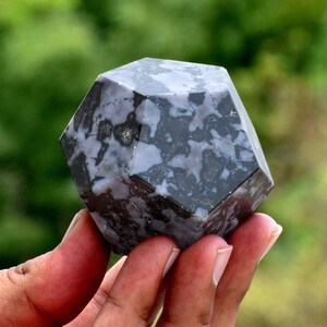 Puede incluir: Una piedra moteada de negro y blanco tallada en forma geométrica. La piedra es un dodecaedro, una forma de 12 lados.