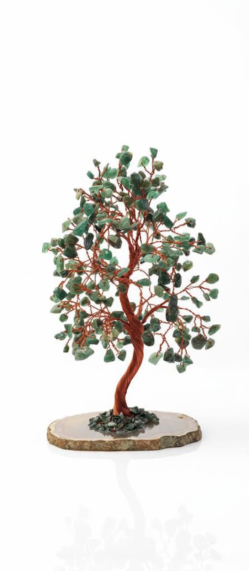 May include: A decorative tree sculpture with a copper wire trunk and branches, adorned with green gemstone leaves. The tree sits on a natural stone base, creating a unique and artistic piece. The base measures approximately 6 inches in diameter.