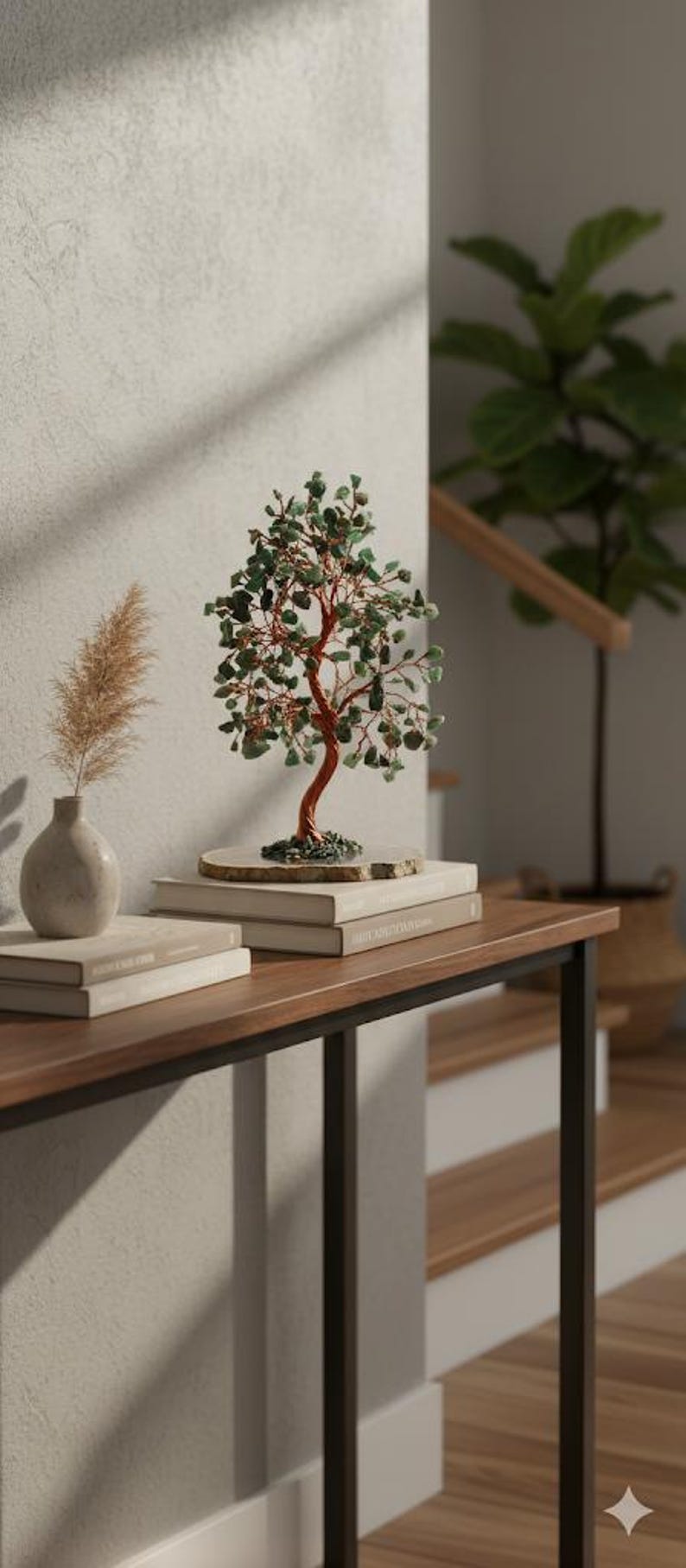 May include: A decorative bonsai tree with a copper-colored trunk and green gemstone leaves sits atop a stack of books on a wooden table. A small vase with dried pampas grass and a potted plant are also on the table.
