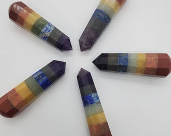 May include: Five multi-colored stone wands arranged in a circular pattern. Each wand features seven distinct horizontal segments in shades of red, orange, yellow, green, blue, indigo, and violet, polished into a smooth, faceted hexagonal point.