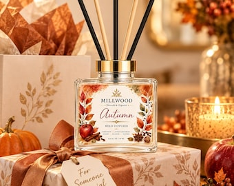May include: A square glass reed diffuser bottle with a gold cap and five black and tan reeds. The label features autumn leaves, a red apple, and text reading Millwood Naturals & Organics Autumn Reed Diffuser 3.21 FL. OZ. / 95 ML.