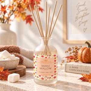 May include: A clear glass room diffuser bottle with a label reading Millwood Maple Mallow, Marshmallow, Maple, Vanilla, 3 oz. The bottle contains liquid and several wooden reed sticks extending upwards from the narrow neck of the glass container.