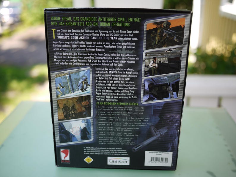 Puede incluir: La parte trasera de una caja de videojuego para "Rogue Spear: Urban Operations" presenta capturas de pantalla del juego y texto en varios idiomas. La caja es principalmente negra con texto verde y blanco, y el logotipo de Ubi Soft es visible.
