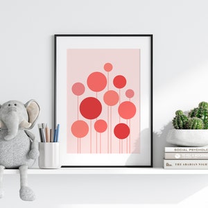 May include: A framed print with a pink background and a design of red and pink circles with thin lines extending from the bottom of each circle. The print is on a white shelf with a gray elephant plush toy, a white cup with pencils, and a potted cactus on a stack of books.