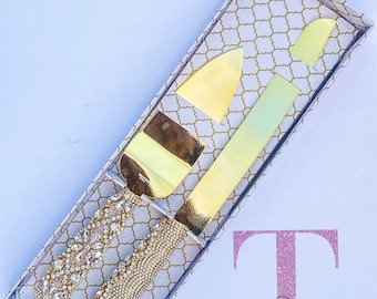 May include: Gold cake knife set with a jeweled handle and a decorative box. The box has a white and gold pattern and the text "Bling Always" in pink glitter.