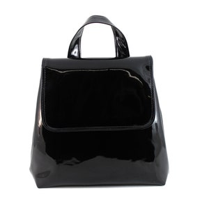 May include: A black patent leather backpack with a single top handle.