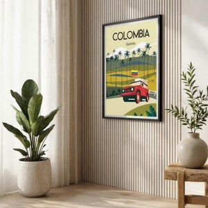 May include: A framed poster with the word "COLOMBIA" and "Salento" printed on it. The poster features a red jeep driving on a road, palm trees, and the Colombian flag. The poster is hanging on a beige wall.