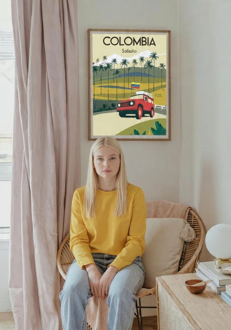 May include: A framed poster with the word "COLOMBIA" at the top, featuring a red vehicle on a road with palm trees. A person wearing a yellow sweatshirt and blue jeans sits in a wicker chair.