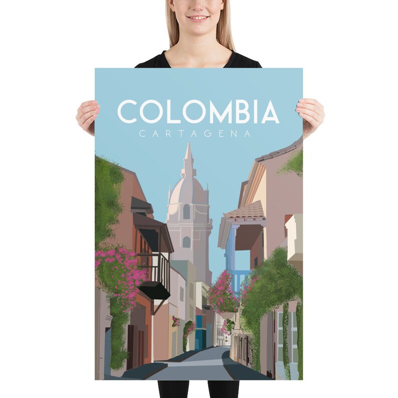 May include: A colorful illustration of a street scene in Cartagena, Colombia. The image features a narrow street lined with colorful buildings, a church with a tall steeple, and lush green foliage. The text "COLOMBIA CARTAGENA" is displayed at the top of the image.