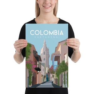 May include: A colorful illustration of a street scene in Cartagena, Colombia. The image features a narrow street lined with colorful buildings, lush greenery, and a tall church in the distance. The text "COLOMBIA CARTAGENA" is displayed at the top of the image.