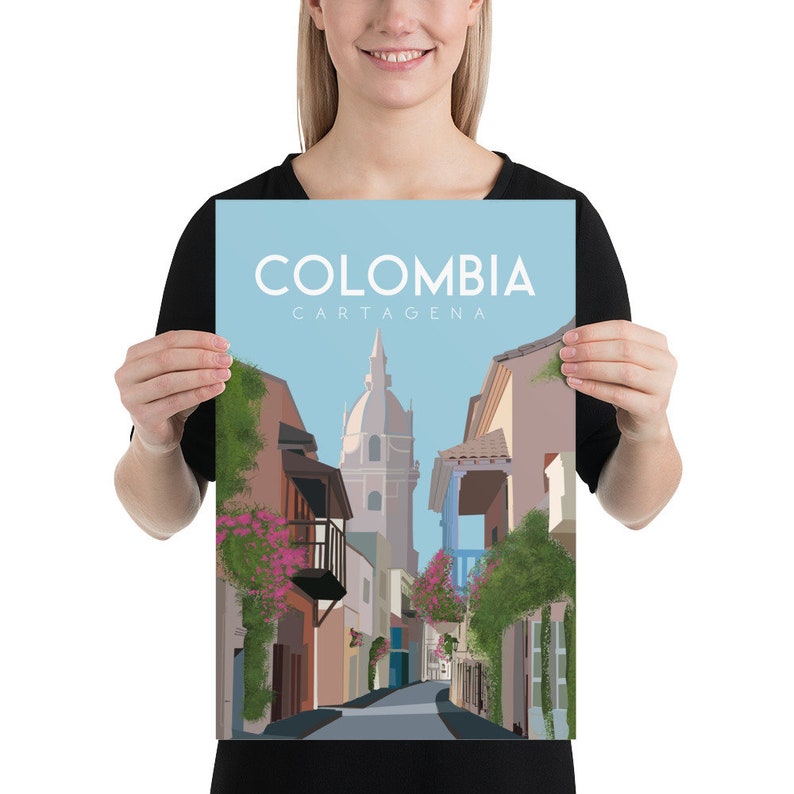 May include: A colorful illustration of a street scene in Cartagena, Colombia. The image features a narrow street lined with colorful buildings, lush greenery, and a tall church in the distance. The text "COLOMBIA CARTAGENA" is displayed at the top of the image.