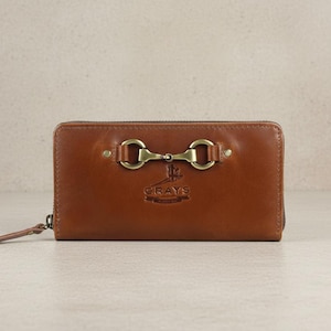 May include: A brown leather wallet with brass-toned bit and ring hardware. The wallet features a zip closure and a wrist strap. The brand name "GRAYS" is embossed on the front.