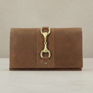 May include: A brown leather wallet with a brass clasp. The rectangular wallet features a vertical strap with a decorative clasp. The leather has a slightly distressed appearance, giving it a vintage feel.