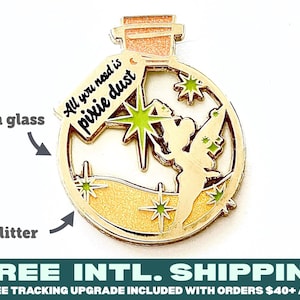 May include: Gold-tone metal pin shaped like a bottle with a cork stopper. The bottle contains a fairy with wings and a star. The bottle has a label that reads "All you need is pixie dust".