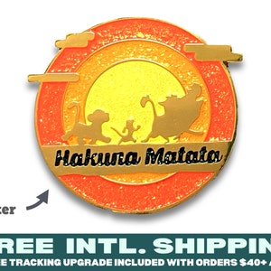 Puede incluir: Un pin de esmalte dorado con un fondo de puesta de sol naranja, amarillo y rojo brillante. El pin presenta la silueta de Simba, Timon y Pumbaa de El Rey León de Disney, caminando a través de la puesta de sol. El texto "Hakuna Matata" está escrito en letras negras sobre una pancarta dorada.