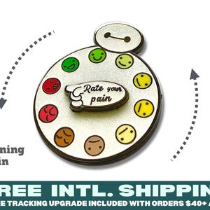 May include: A circular metal enamel pin featuring a white base with a character head at the top and a rotating pointer in the center. The pointer displays the text Rate your pain. Surrounding the center are ten colorful emoji faces.