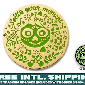 May include: A gold-colored circular pin with a green enamel design. The design features a stylized skull with a smile and floral patterns. The text "Seize your moment" is written around the edge of the pin. The pin glows in the dark.
