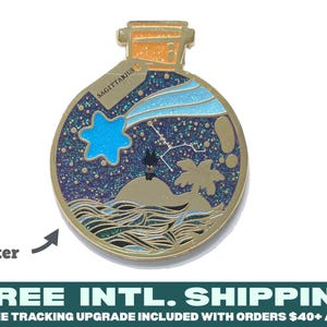 May include: A gold-toned metal enamel pin shaped like a potion bottle. The design features a dark blue glitter night sky with a light blue shooting star, a small island with a palm tree, and wavy water. The text SAGITTARIUS is printed on a small tag.