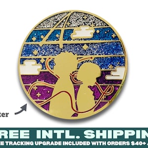 May include: Gold-colored enamel pin with a glitter finish. The pin depicts two figures standing side-by-side against a purple, blue, and white background with a starry sky. The pin is round and has a shiny finish.