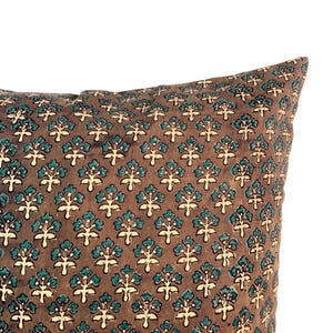 May include: Close-up of a brown pillow with a repeating floral pattern in teal and cream. The pillow has a soft, textured appearance, and the pattern is evenly distributed across the fabric. The design gives a vintage or bohemian feel.