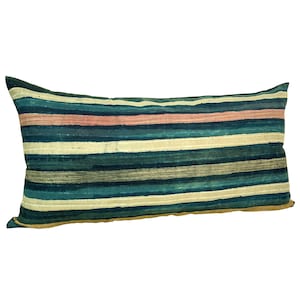 May include: A rectangular lumbar pillow featuring a horizontal striped pattern in shades of deep teal, dark blue, muted cream, and soft dusty pink. The fabric displays a textured, woven appearance with varied line widths across the entire surface.