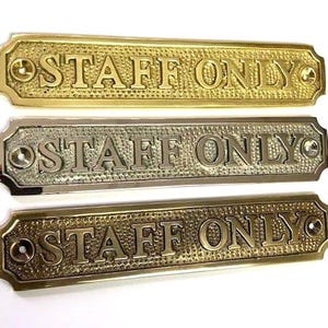 May include: Three rectangular metal signs with rounded corners, each featuring the embossed text "STAFF ONLY" in capital letters. The background of each sign has a textured, hammered finish, and each end includes a pre-drilled hole for mounting.