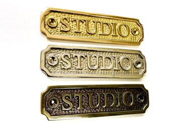 Studio door sign available in three finishes - nickel, antique bronze or brass. Matching screws are included. 12 cm X 3.3 cm.