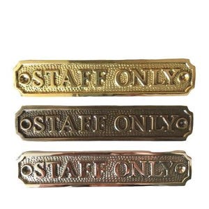 May include: Three rectangular metal signs with a textured background and the embossed text STAFF ONLY. The top sign is polished gold, the middle is dark bronze, and the bottom is a copper-toned metal. Each sign has two screw holes for mounting.