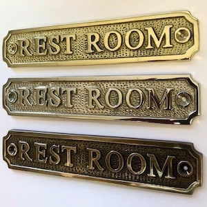 Letrero para puerta de baño disponible en tres acabados: níquel, bronce antiguo o latón. Se incluyen tornillos a juego. 16,7 cm X 3,4 X 0,4 cm
