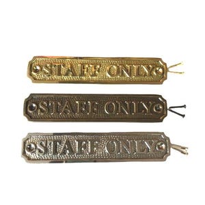 May include: Three rectangular metal signs with a textured background and the embossed text "STAFF ONLY" in capital letters. Each sign features a screw hole on both ends and includes two small mounting screws attached to the right side.