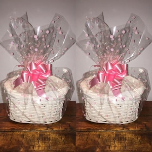 May include: Two white wicker baskets with pink polka dot cellophane wrapping and pink satin bows.