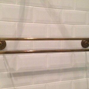 Double embossed towel rail, solid brass with an antiqued bronze finish, 60 cm wide embossed decorative pattern. Matching screws provided.