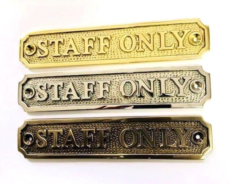 May include: Three rectangular metal signs with rounded corners, each featuring the embossed text "STAFF ONLY" in capital letters. The signs have a textured background and a screw hole on each end, presented in polished brass, chrome, and antique bronze finishes.