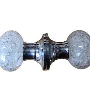 May include: A pair of clear glass door knobs with a chrome finish. The glass has a textured bubbled effect.