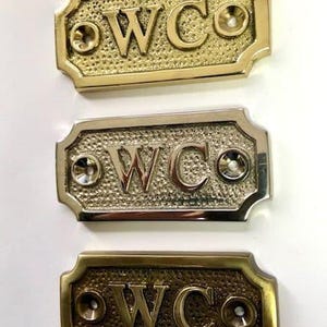 WC door sign available in three finishes - silver nickel, antique bronze or brass. Matching screws are included. 7 cm X 3.3 cm. Toilet door