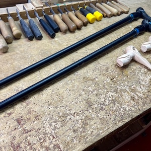 May include: Two black wooden walking sticks with carved bird head handles. The handles are unfinished wood and the sticks are black.