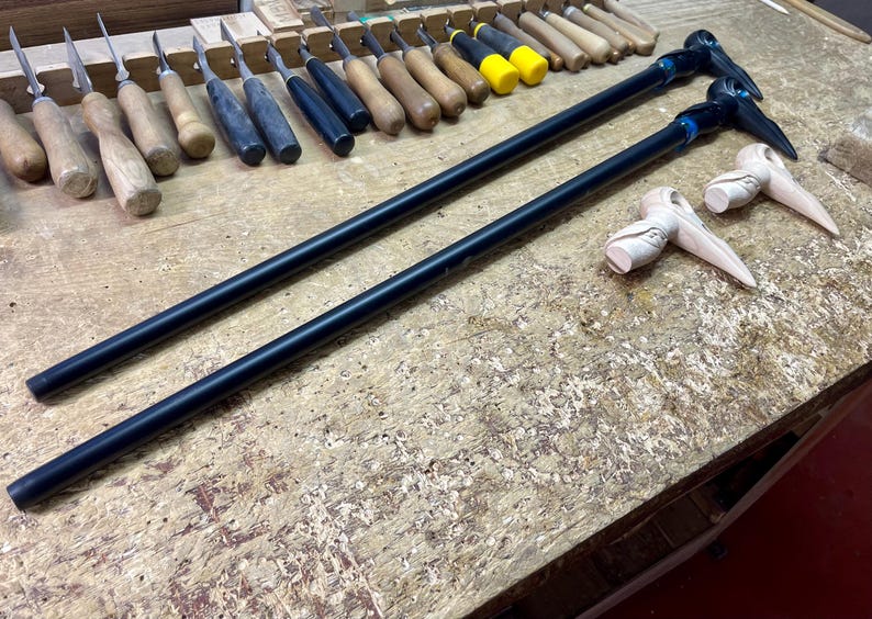 May include: Two black wooden walking sticks with carved bird head handles. The handles are unfinished wood and the sticks are black.