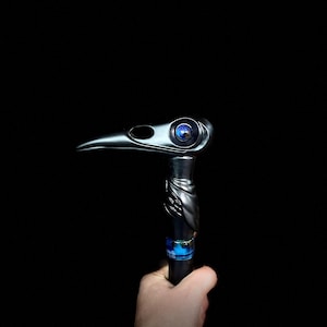 May include: A black walking stick with a bird head design. The bird's eye is a blue glass orb.