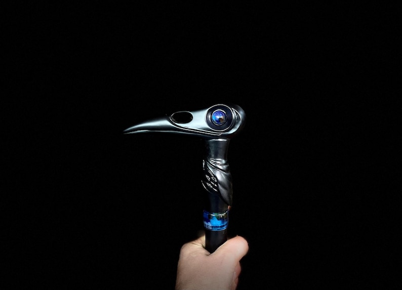May include: A black walking stick with a bird head design. The bird's eye is a blue glass orb.