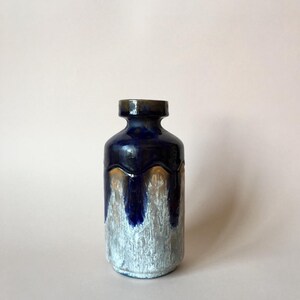 May include: A blue and white ceramic vase with a brown glaze. The vase has a rounded body and a narrow neck.