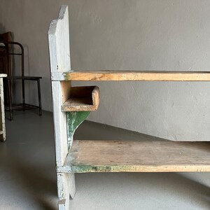 May include: A wooden shelf unit with three shelves. The shelves are painted white and green. The unit has a rustic, vintage look.