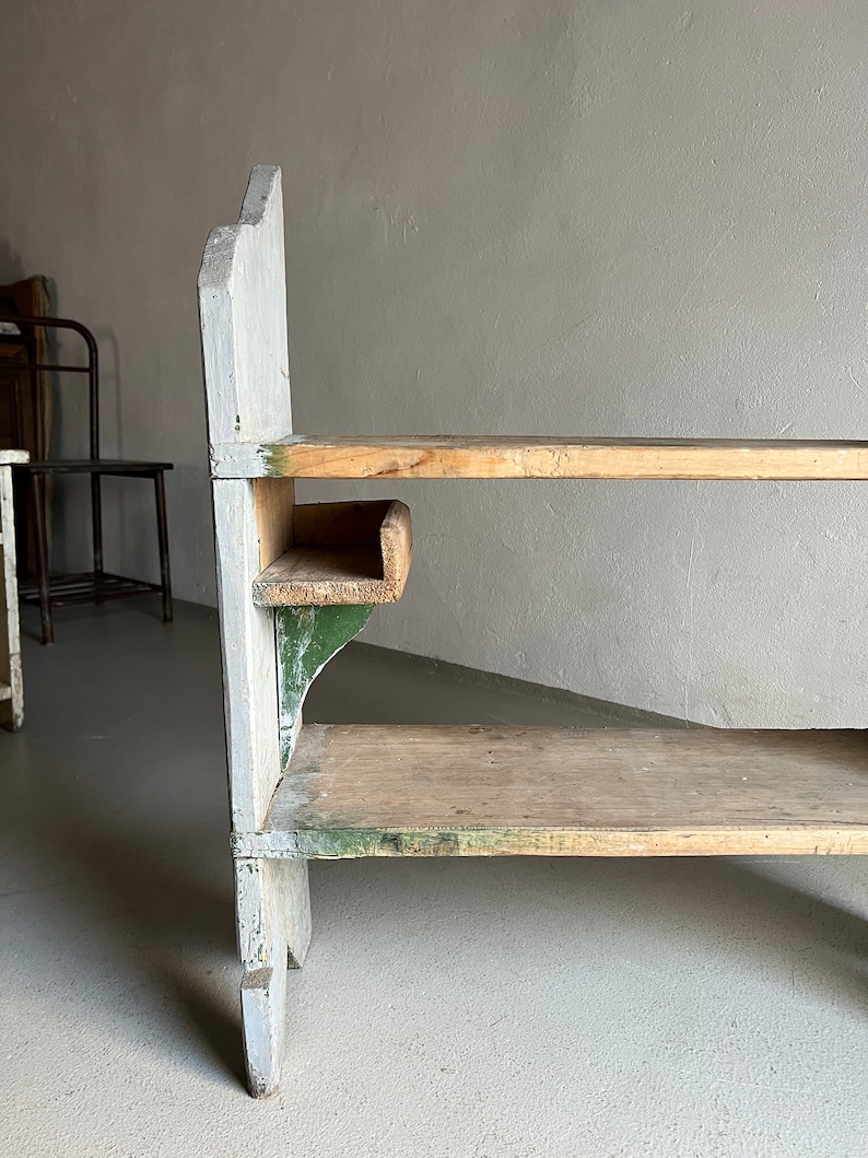May include: A wooden shelf unit with three shelves. The shelves are painted white and green. The unit has a rustic, vintage look.